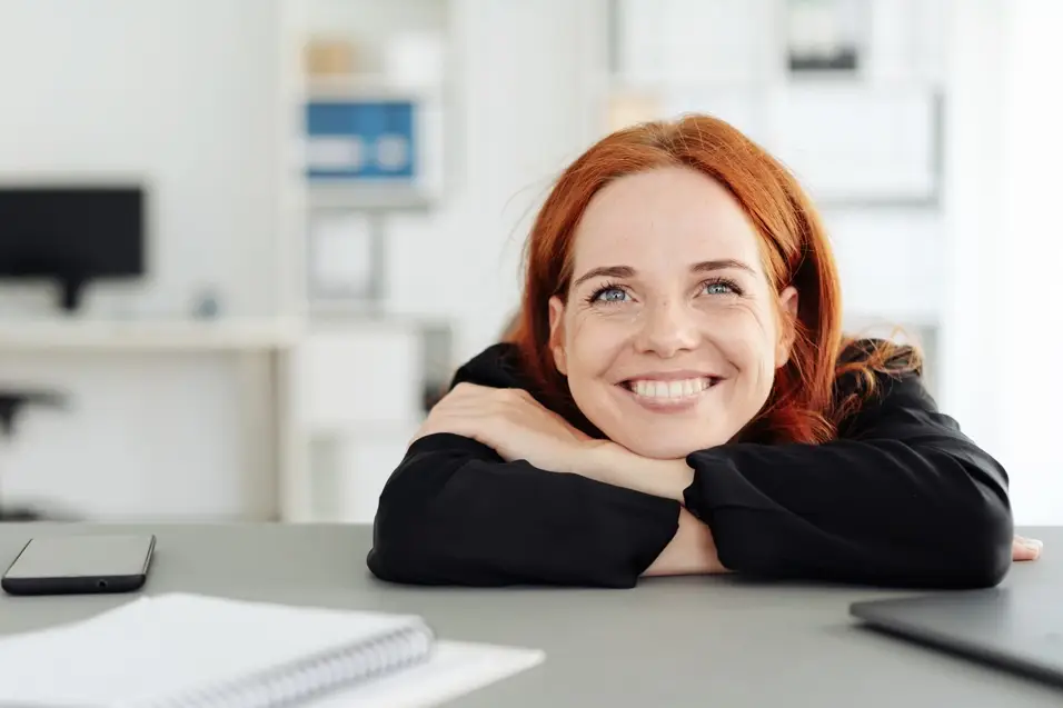 Smiling customer resting her chin on her hands at a desk, representing DocTech’s happy and satisfied clients.